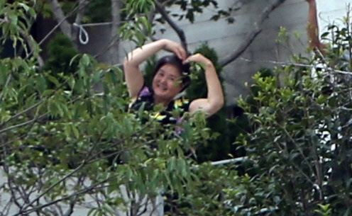 문재인 대통령의 지지자들이 17일 사저가 있는 경남 양산시 하북면 지산리 평산마을에 모여 평산마을 평온 회복과 문 전 대통령 부부 안녕을 기원하는 집회를 진행하자, 문 전 대통령의 부인 김정숙 여사가 사저 바깥으로 잠깐 나와 지지자들을 향해 팔로 하트를 만들고 있다. 연합뉴스.